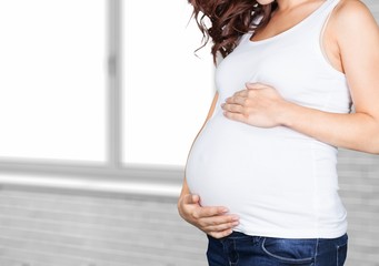 Pregnant young woman in white t shirt on  background