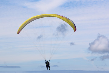 Tandem paraglider flying yellow wing