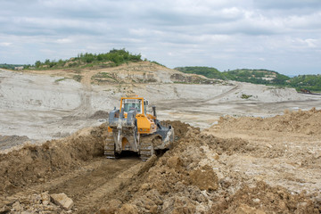 Bulldozer moving marl and limestone over the quarry edge