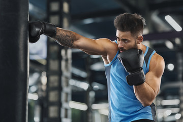 Fototapeta na wymiar Young sportsman boxing workout at gym interior
