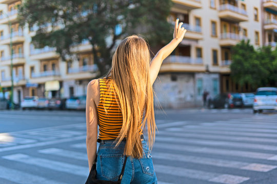 Rear view of teenage girl hailing taxi