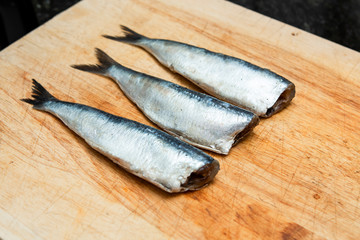 fresh sardines on a wooden chopping board