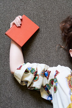 Female student holding red book in a public library