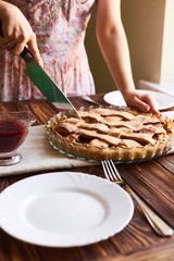 woman cutting a dessert of freshly baked apple pie on wooden the table