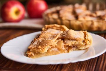 Eating sweet food context. Traditional holidays apple pie, slice on white plate and apples. Relishing sweet treats
