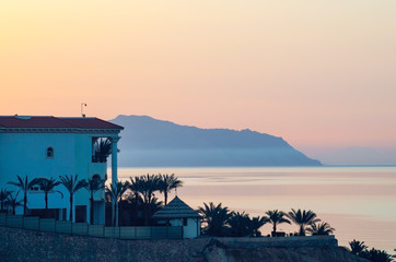 Obraz premium View of the hotel building, the sea and the mountains at sunrise, dawn at a resort in Egypt