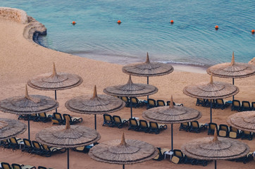 Reed umbrellas with loungers on a beautiful sandy beach