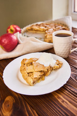 Tasty homemade apple pie, slice with ice cream. Apples. Plate, linen towel Wooden background Cup of tea