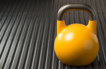 Yellow weight lifting exercise kettlebell on a gym mat