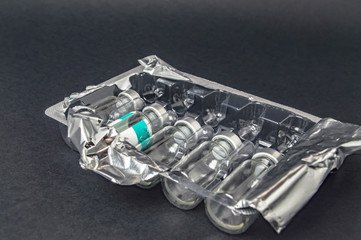 Glass bottles from vaccine in plastic packaging with foil close up