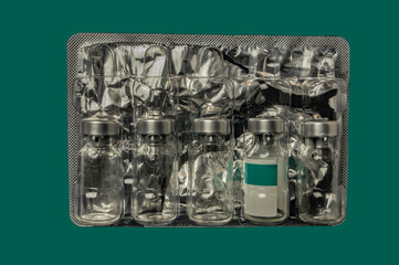 Glass bottles from vaccine in plastic packaging with foil close up