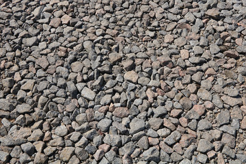 Stone rubble for use as a background or texture with a cement stain. Gray light stones on a dirt road