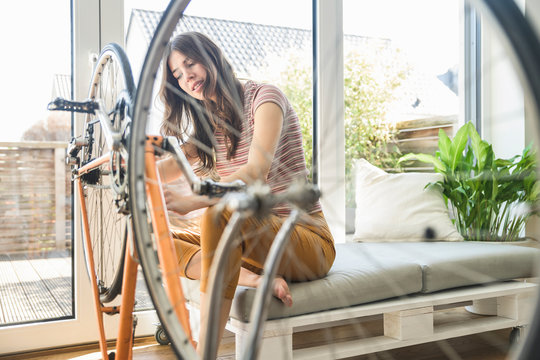 Young woman repairing bicycle at home