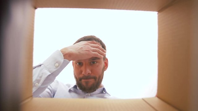 presents, delivery and bad surprise concept - disappointed man opening parcel box with something unpleasant