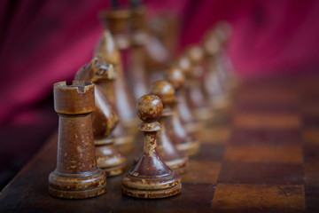 Closeup of vintage wooden chess pieces standing on a chessboard, concept of a game of chess as a business, success