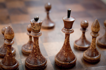 Closeup of vintage wooden chess pieces standing on a chessboard, concept of a game of chess as a...