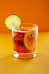 Cola with ice, slice of lemon and lime on orange background