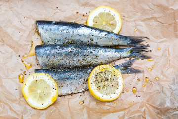 fresh sardines and lemons on brown cooking parchment