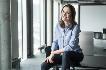 Smiling businesswoman sitting on conference table in office
