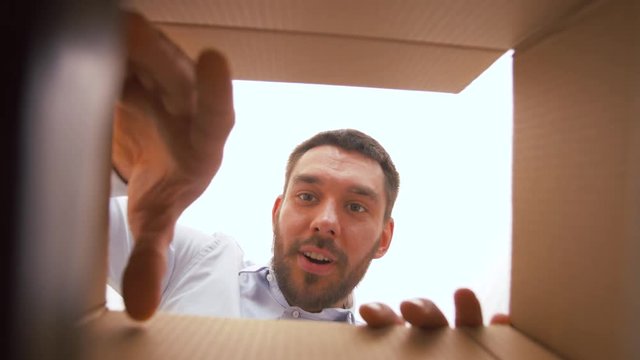 presents, delivery and surprise concept - happy man opening parcel box