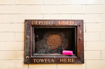 Wooden hatch at an old Victorian public baths swimming pool "deposit used towels here" with a bar of red carbolic soap.