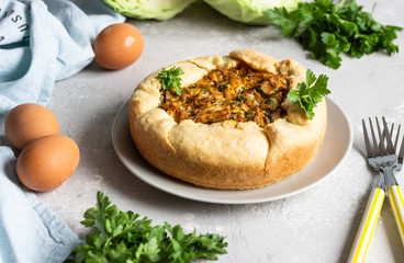 Pie with cabbage, eggs and parsley filling. Light stone background. 