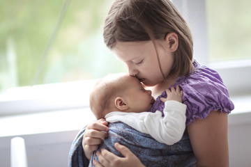 newborn baby in sling with rings with sister