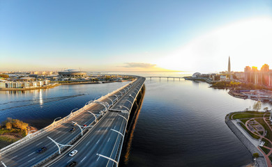 Aerial view of Football stadium Zenit Arena at sunset and new road - Western High Speed Diameter connecting Krestovsky and Vasilyevsky Islands. Bridge Viaduct above Neva river. St. Petersburg, Russia.