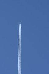 Straight vertical airplane trail in clear blue sky