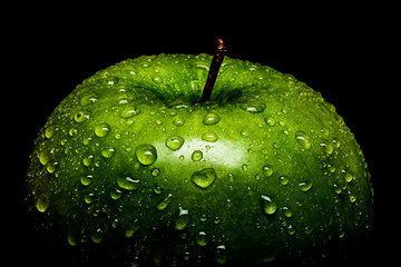 A Frame filling Macro image of a vibrant Green Granny Smith apple covered in water drops beading on the peel.