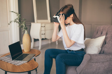 Obraz premium Young female programmer testing a new app with virtual reality glasses in home