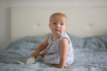 Fototapeta premium Bald Caucasian baby 10 months playing with comb