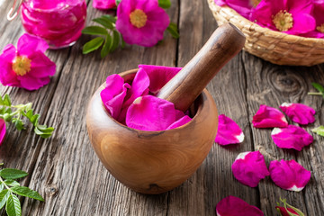 Fresh rosa rugosa petals in a wooden mortar