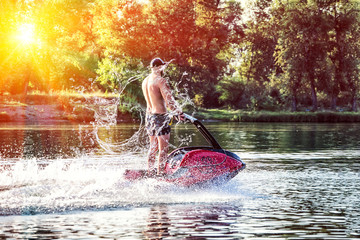 Young man riding water scooter at sea lake river on summer day.