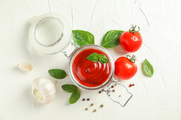 Flat lay composition with fresh tomatoes, basil, pepper, garlic and sauce in glass jar on white background, space for text and top view