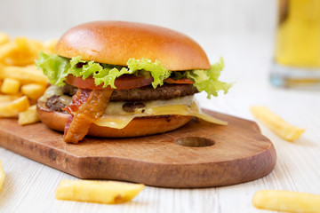 Hamburger, french fries and glass of cold beer on a white wooden background, side view. Close-up.