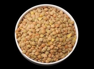 lentils in a white plate isolated on black background. top view