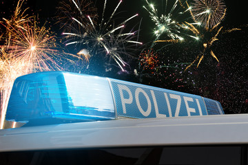 Polizeiwagen mit Blaulicht vor einem Feuerwerk an Silvester