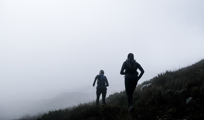 Two trail runners high up on on a mountain with mist © chris