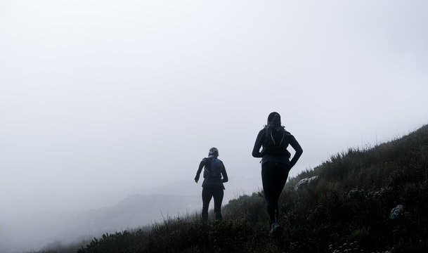 Two trail runners high up on on a mountain with mist