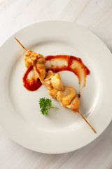 Chicken on bamboo skewers kebab in white plate, marble bright background. Diet low fat food.