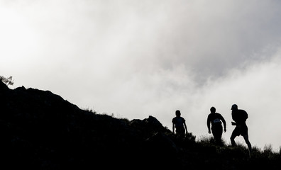 Silhouette of trail runners high up on on a mountain with mist