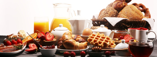 Huge healthy breakfast on table with coffee, orange juice, fruits, waffles and croissants. Good morning concept.