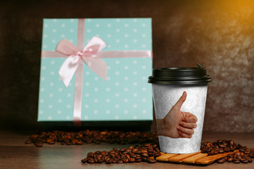 Paper cup for coffee. Grains lie on a wooden surface.
