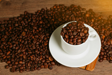 Coffee beans inside white cup standing on a wooden table
