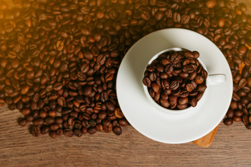 Coffee beans inside white cup standing on a wooden table