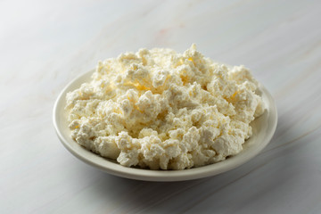 Cottage cheese isoalted on light, marble background. Dairy products, calcium and protein. Healthy breakfast.