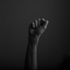 Raised clenched fist against a dark background, power, protest concept