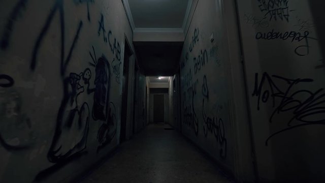 Old Apartment,Ghetto Building,long Dark Hallway.Tracking inside a dark long hallway of a ghetto apartment complex.Graffiti vandalism and abandonment in a poverty stricken neighbourhood.