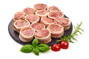 Raw meat medallions wrapped in bacon on a slate shale plate, close-up, isolated on white background